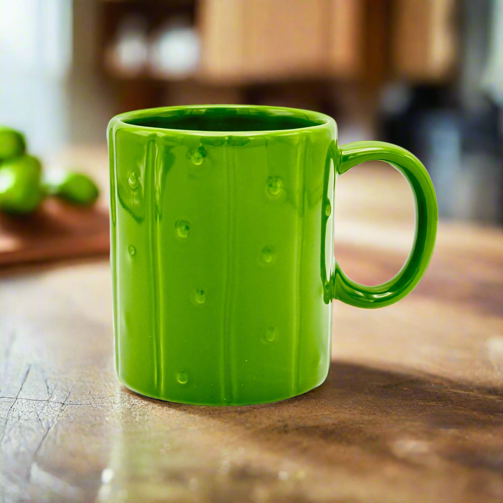 A green ceramic mug designed to resemble a pickle with a handle on the right side.