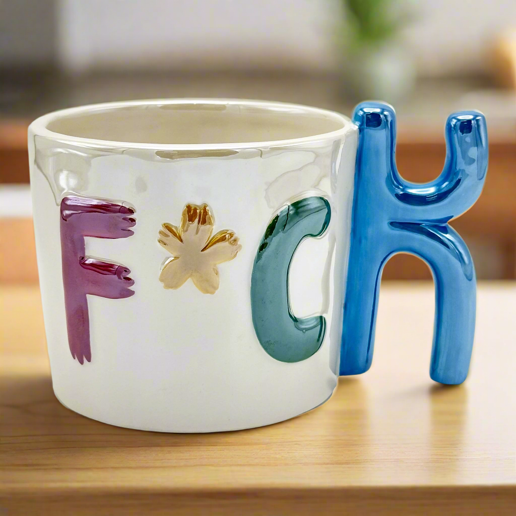 A ceramic mug with a unique 'k' shaped handle, featuring a multicolor design and the word 'F*CK' displayed on it.