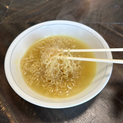 Noodles in a bowl with chopsticks on a wooden surface